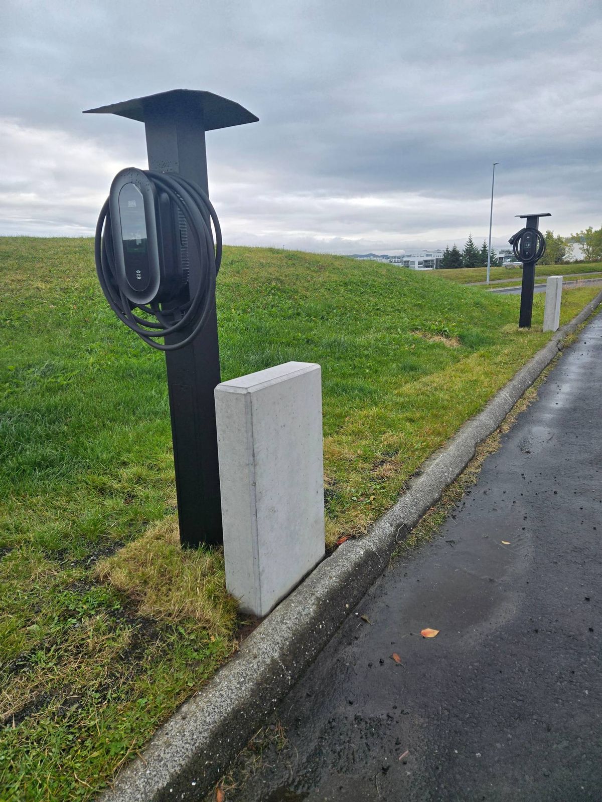 DEFA-stöðvar á svörtum staurum við bílastæði fjölbýlishúss